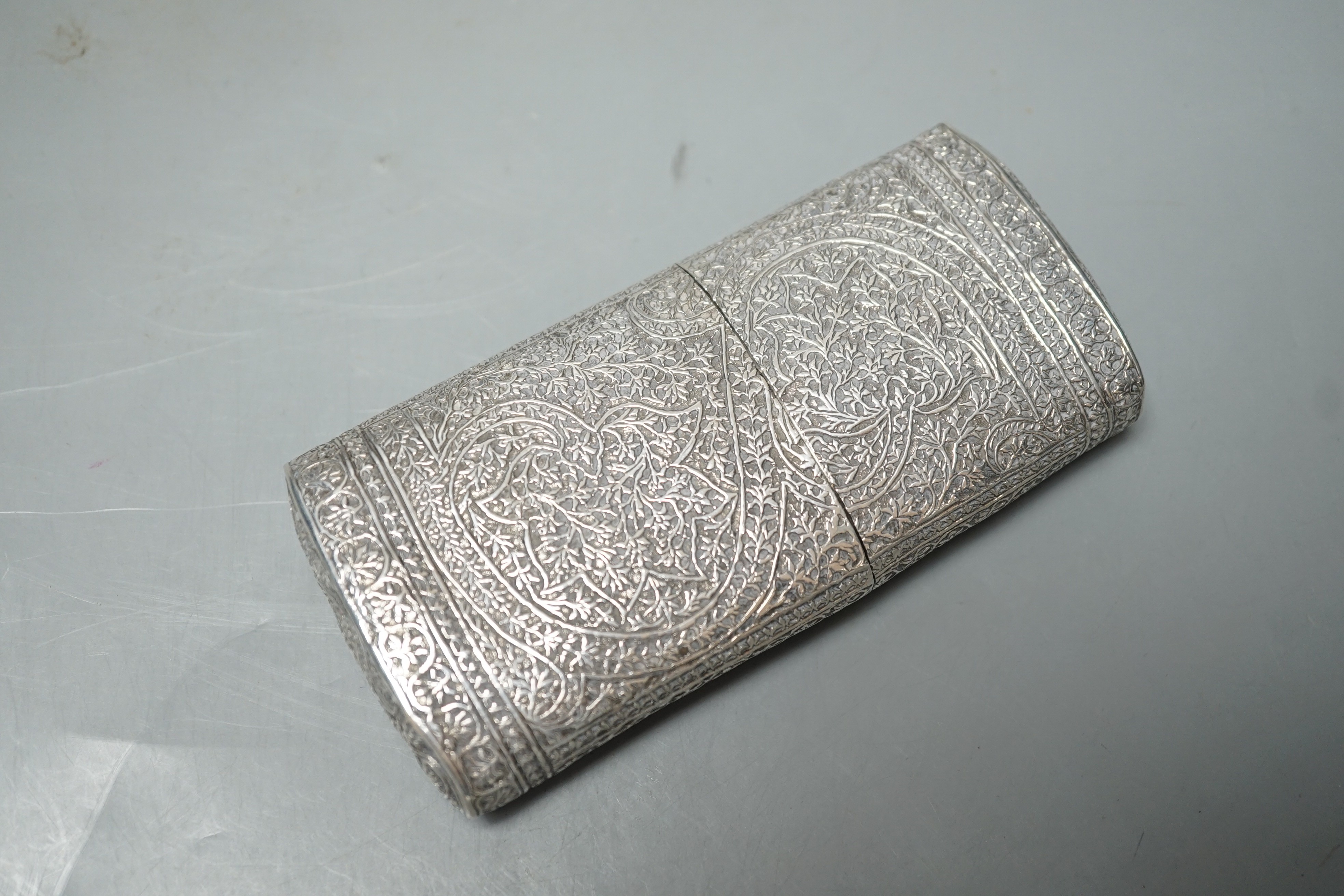 An Indian embossed white metal cigar case, 12.2cm and a similar canister and cover.